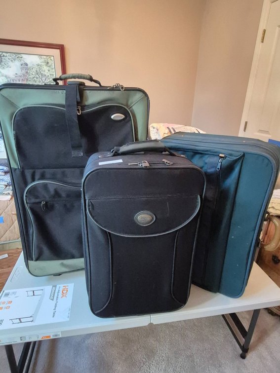 Three Rolling Luggage Bags in Various Sizes and Colors