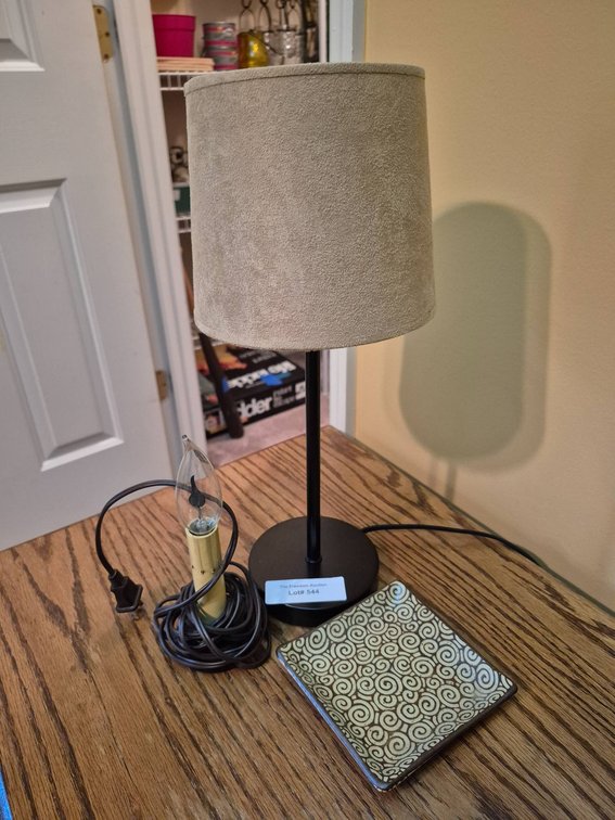 Black Table Lamp With Beige Shade, Candle Bulb, and Decorative Plate