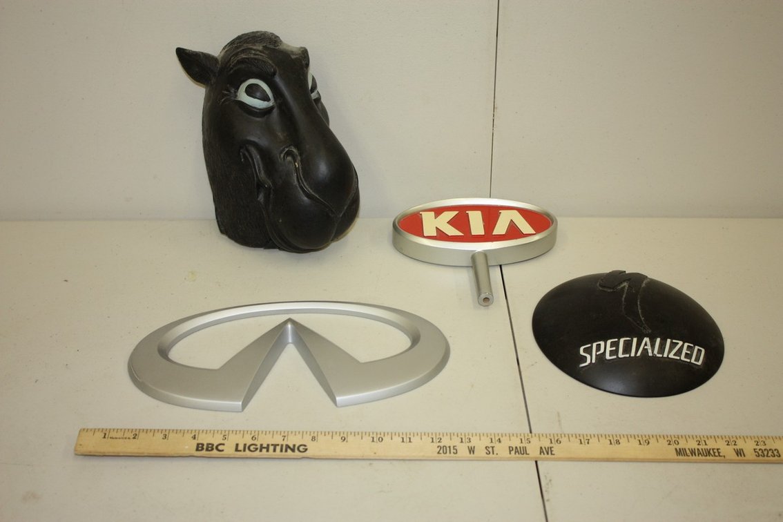 LOT OF FOUR VINTAGE POINT OF SALE MOLDED ADVERTISING SIGNS, INFINITI, CAMEL JOE, SPECIALIZED, AND KIA