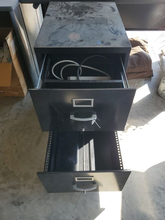 Lot 172: Black Metal 2-Drawer File Cabinet with Assorted Surge Protectors