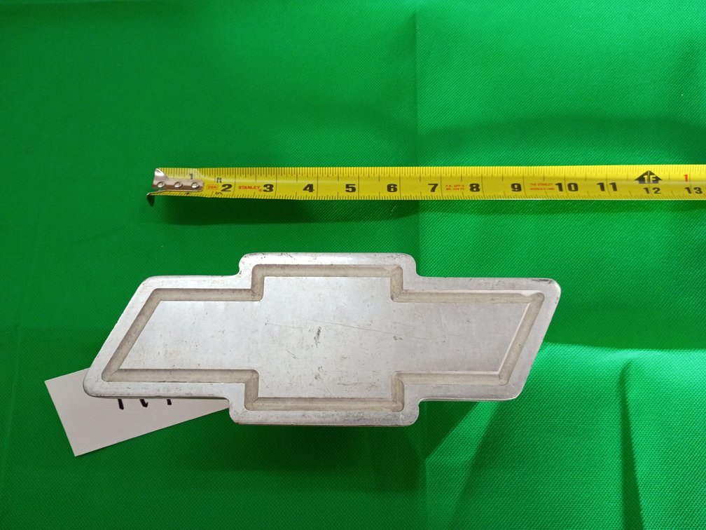 silver metal Chevrolet bowtie trailer hitch receiver cover designed to fit standard 1.25-inch and 2-inch hitch receivers.