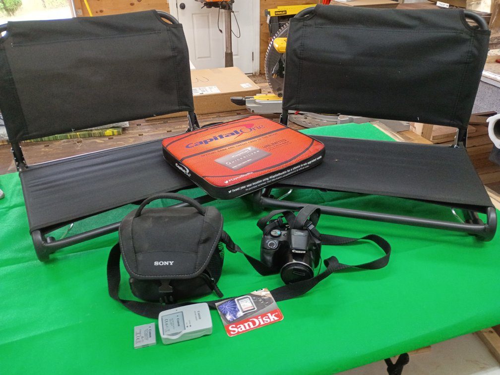 black Canon PowerShot SX530 HS bridge digital camera equipped with a 50x optical zoom lens with two chairs