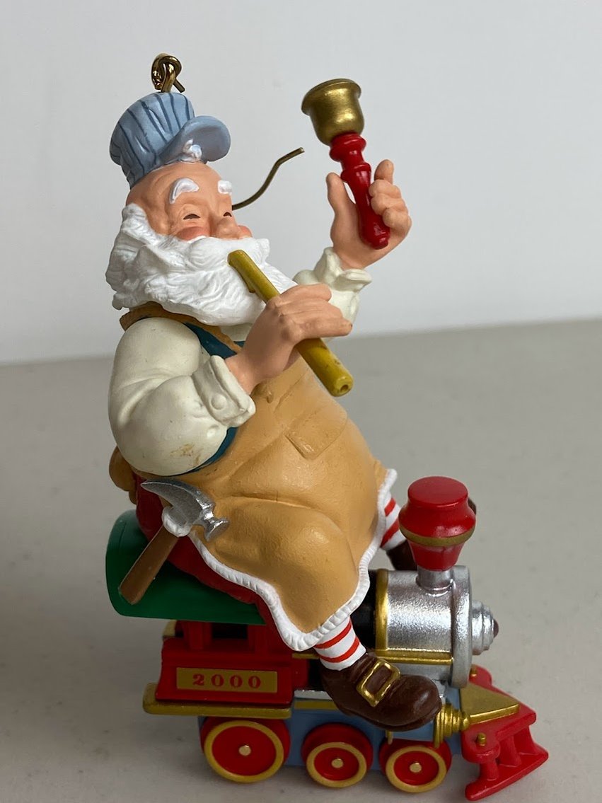 Hallmark 2000 Santa has tan apron on sitting on a Silver and red train with a bell-no box